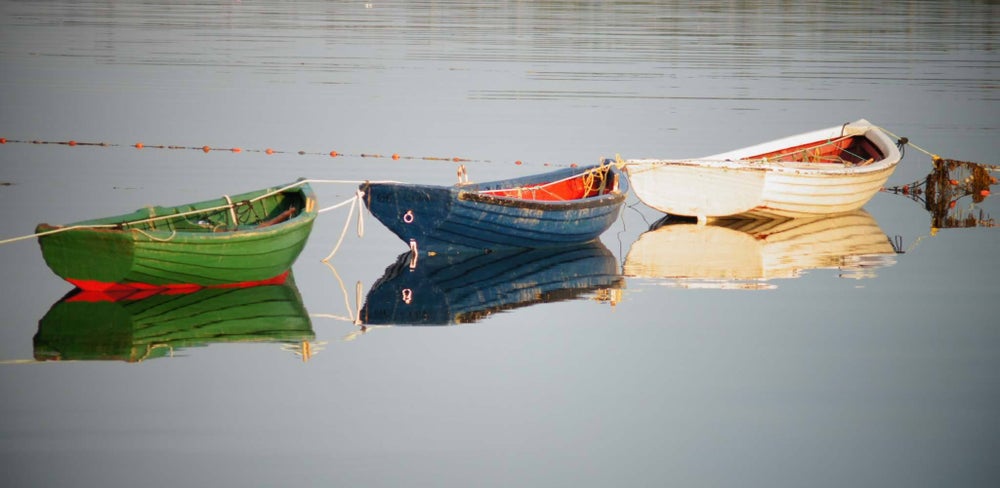 Colourful small boats floating on calm water in St. Margaret’s Bay with clear reflections and coastal setting in Nova Scotia