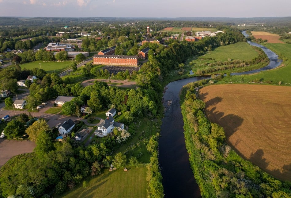 Aerial view of Bible Hill, Nova Scotia, showing homes along the river with Truro and agricultural fields in the background.