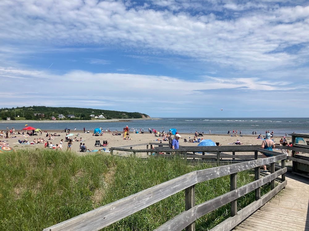 People enjoying the sandy shoreline at MacCormacks Beach Provincial Park in Eastern Passage, Nova Scotia, with boardwalk access, grassy dunes, and ocean views