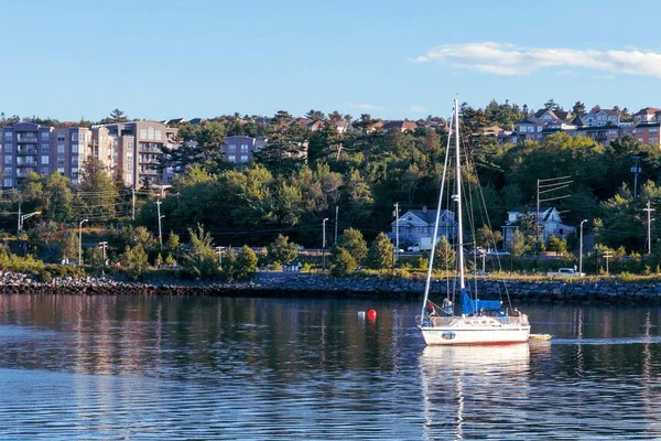 Sailboat on the Bedford Basin with homes and waterfront along the Bedford shoreline near Halifax Nova Scotia