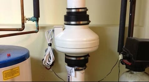 Radon mitigation system installed in a basement, showing a sub-slab depressurization pipe and fan used to reduce radon gas levels in a home.