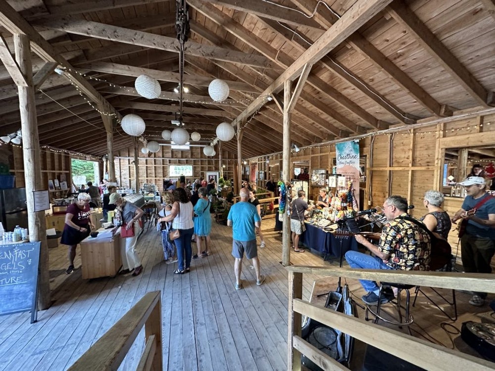Inside the Hubbards Farmers’ Market with local vendors, shoppers, and live music in a rustic wooden barn in Nova Scotia