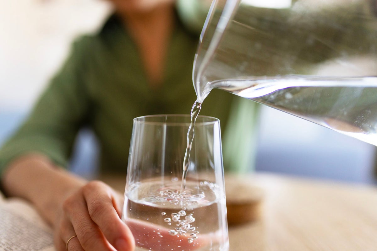 Close-up of clear drinking water poured into a glass, symbolizing clean and properly tested private well water in a home.