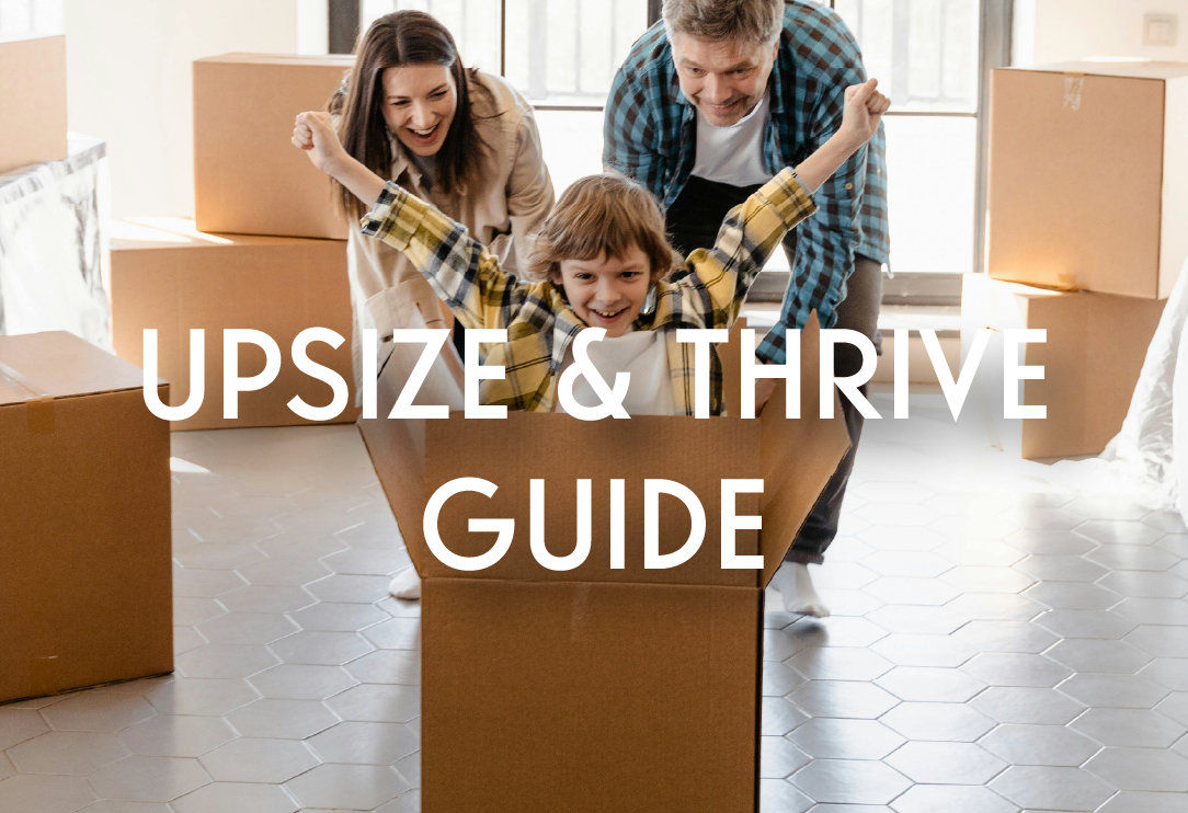 a man and woman smiling pushing their smiling son with his arms raised in a box