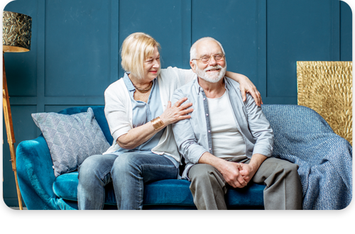 An elderly couple sitting on a couch smiling