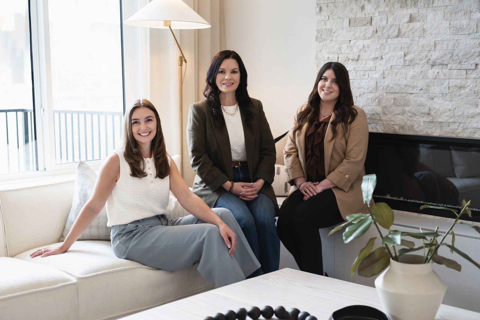 Jenna Bole Real Estate Team members Jenna Bole, Crystal Jepp and Julia Barrett sitting on a couch in a listing they have sold
