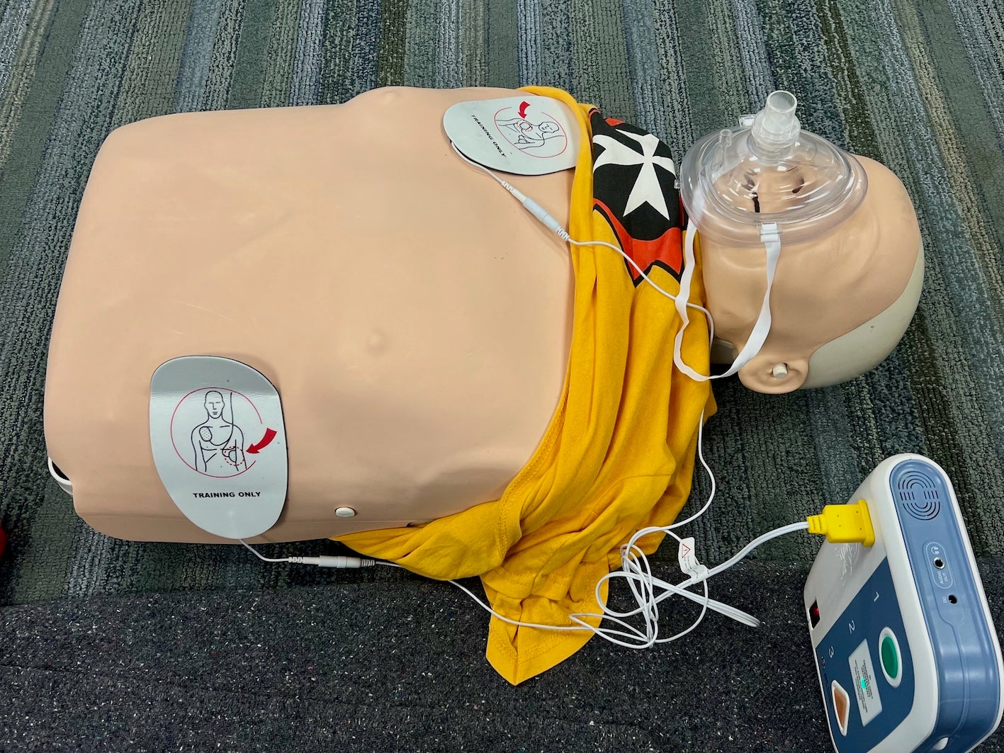 CPR training mannequin and automated external defibrillator used during St. John Ambulance first aid and lifesaving certification training.