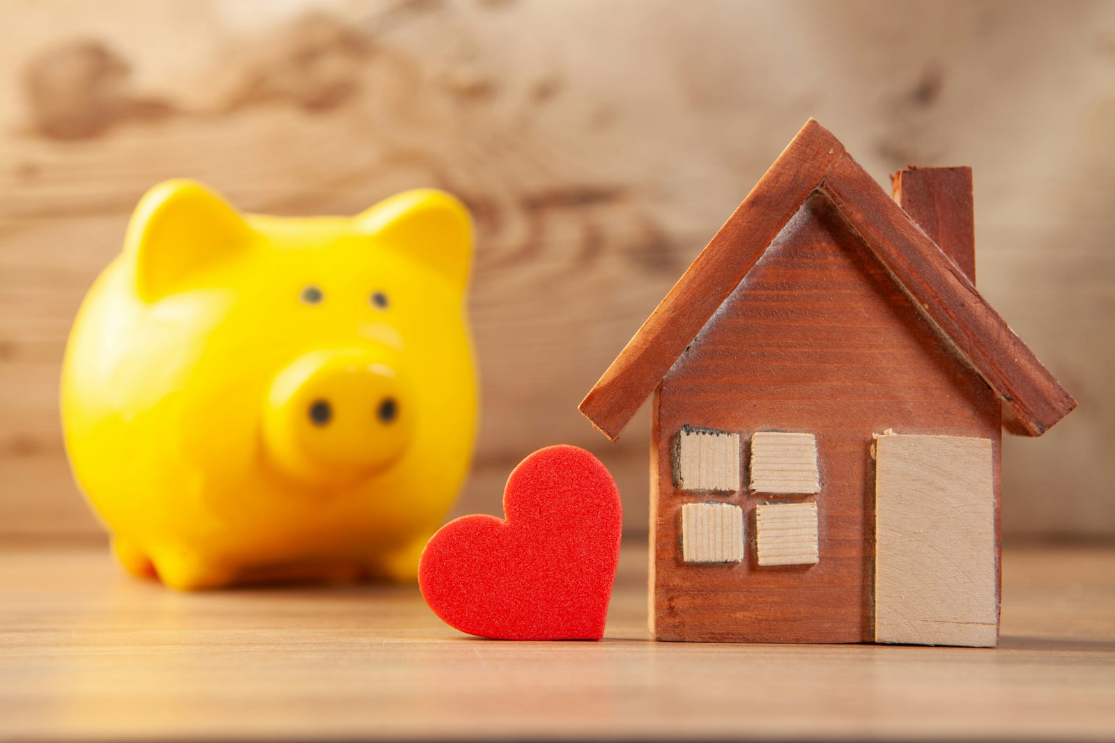 House model with a piggy bank and heart symbol representing the financial and personal value of homeownership in retirement planning.