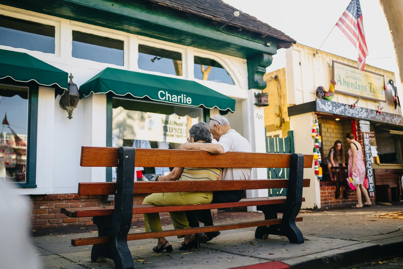 Older couple sitting on a bench in a sunny coastal town representing the snowbird lifestyle.