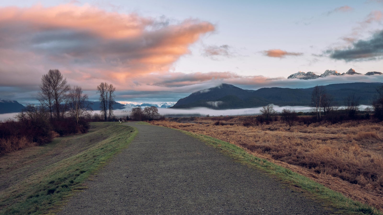 Pitt Meadows dyke at sunrise with mountain views and walking trail in Greater Vancouver