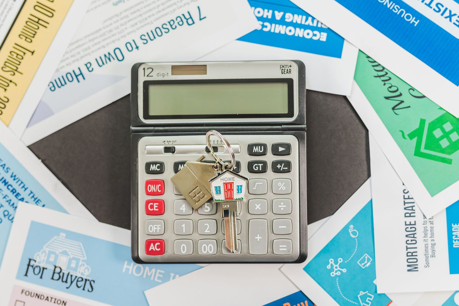 Calculator and house keys on mortgage documents, illustrating the financial analysis required when comparing renting and buying.
