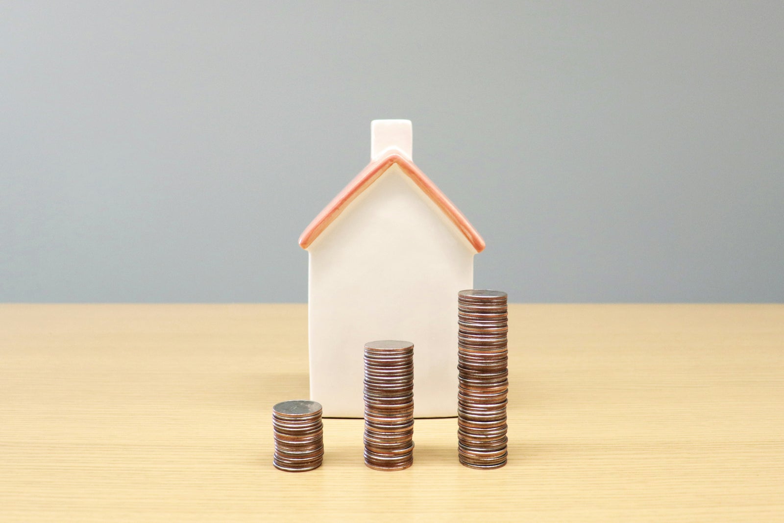 House model beside stacks of coins illustrating how home equity can grow over time as part of a retirement plan.