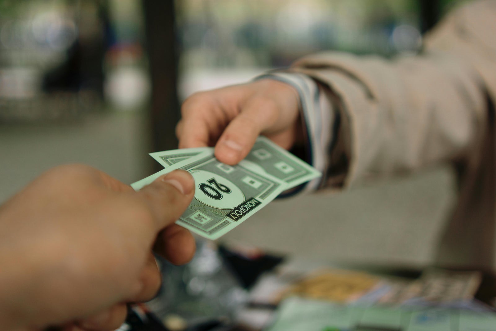 Hands exchanging Monopoly money representing cosigning for someone else while applying for a mortgage and how it can affect mortgage approval