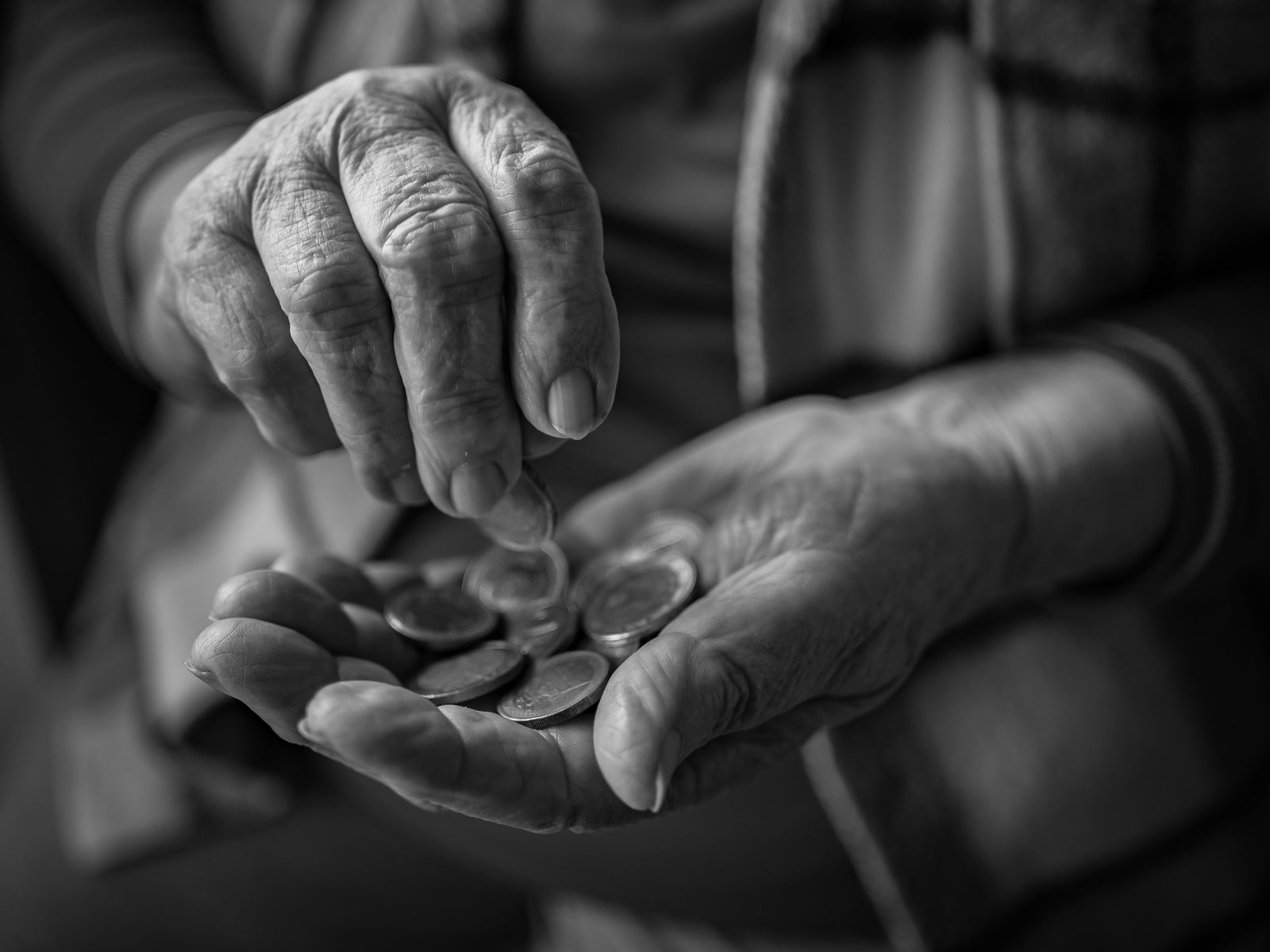 Elderly person counting coins in their hands, highlighting the financial challenges of housing affordability and rising living costs.
