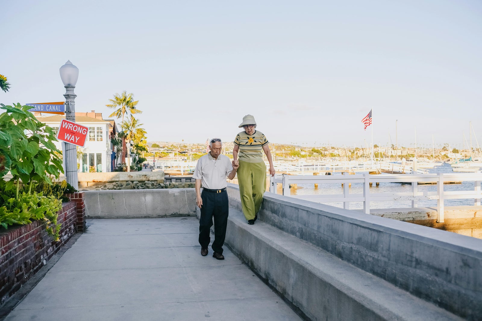 Older couple walking along a waterfront promenade representing Canadian snowbirds returning home after winter abroad.