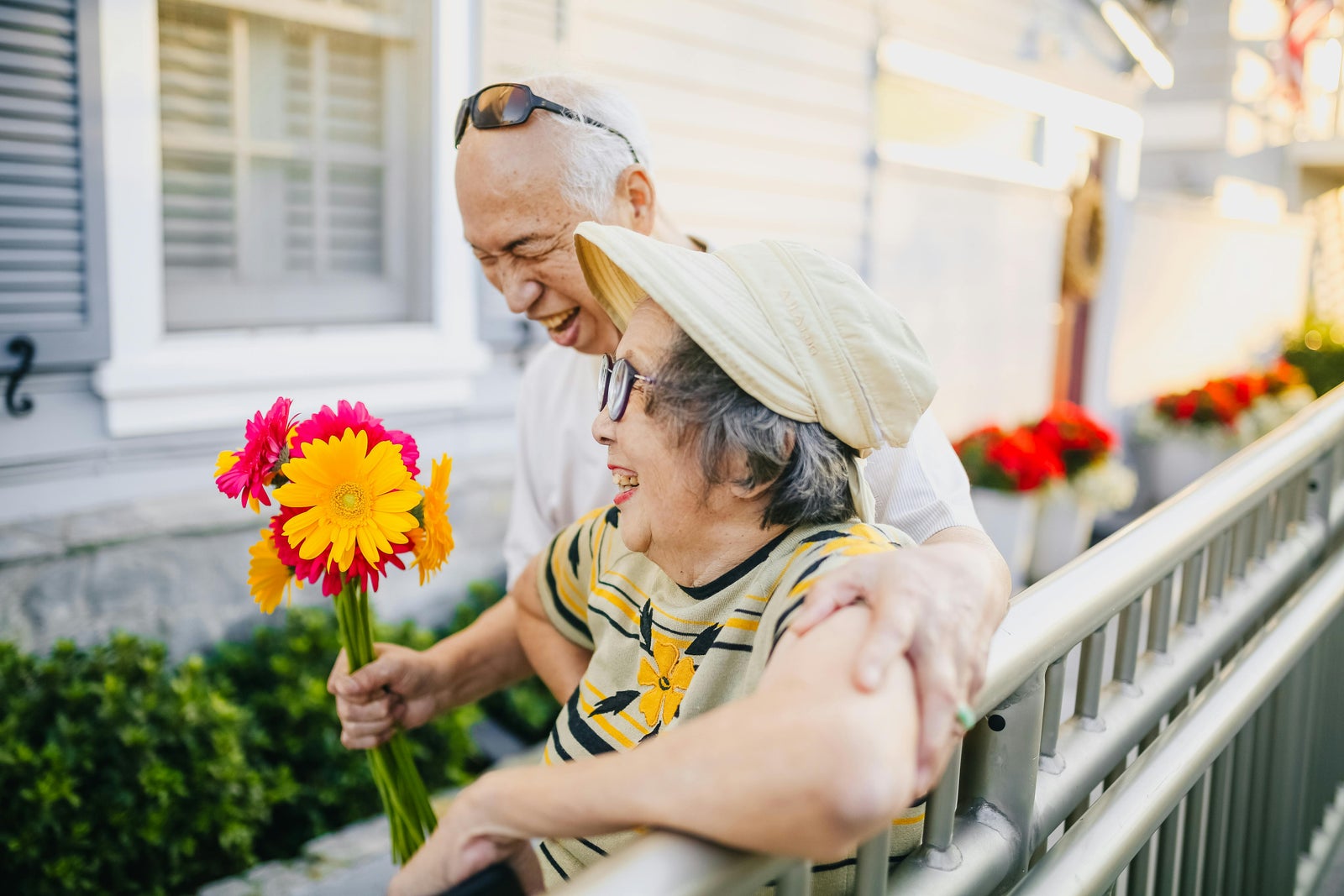 Older couple smiling and holding flowers symbolizing Canadian snowbirds enjoying warm winter destinations.