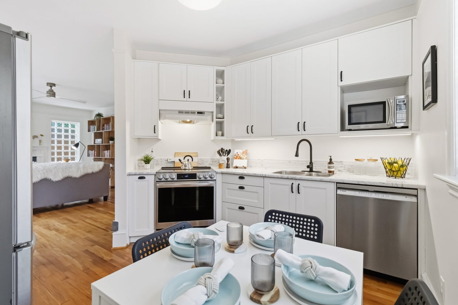 White shaker kitchen with stainless steel appliances and under cabinet lighting in a Fernwood townhouse for sale