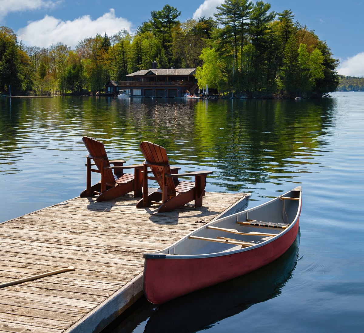 Muskoka chairs on a dock and canoe dockside on Manitoulin Island. 