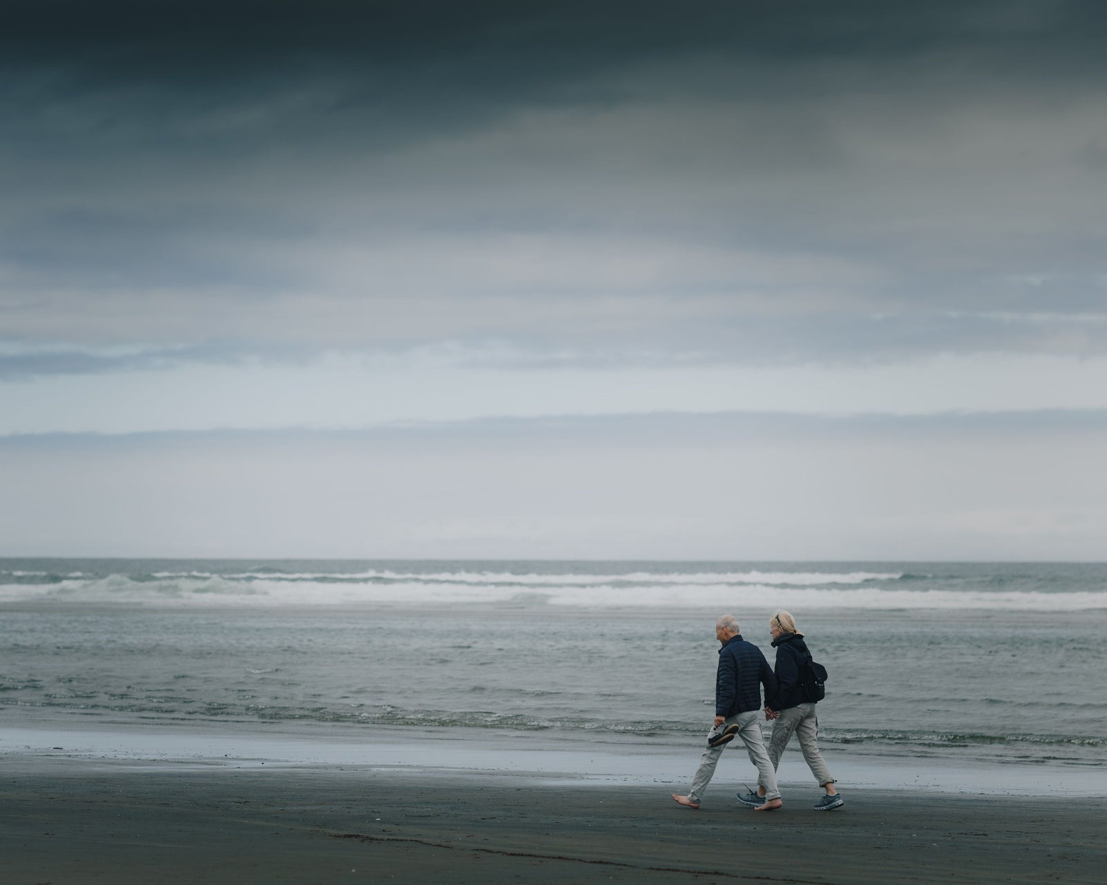 Mature couple walking along a beach during a mild coastal winter