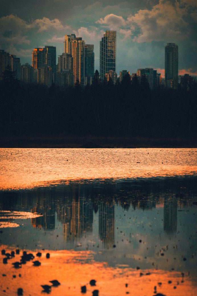 Burnaby skyline at sunset, with reflections on the water, highlighting the city's modern real estate landscape