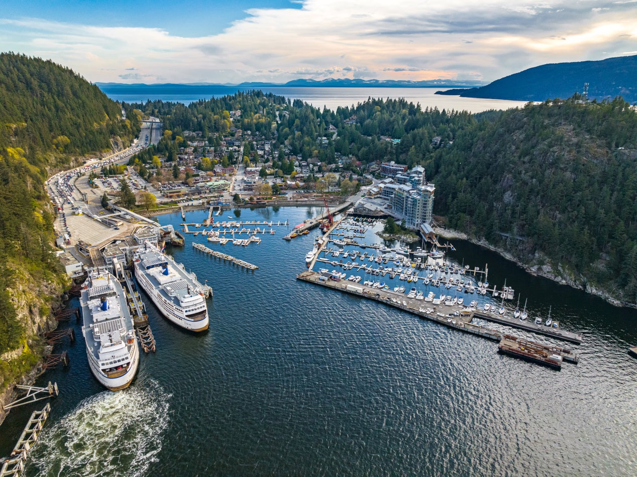 Aerial view of Horseshoe Bay in West Vancouver, showcasing marina, ferry terminal, and luxury real estate nestled among lush greenery