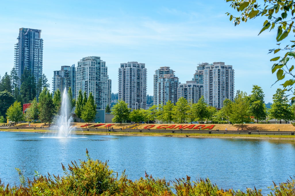 View of high-rise residential buildings in Coquitlam, with a fountain in the foreground, showcasing prime real estate opportunities in the area