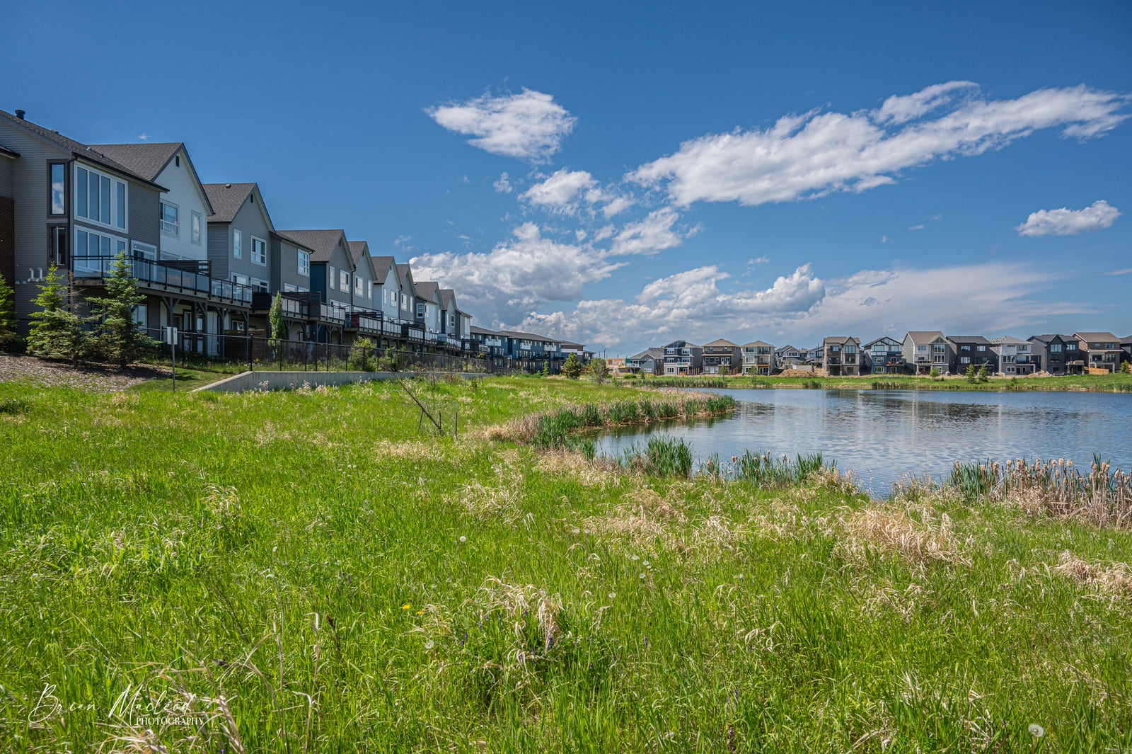 townhouses overlooking storm water pond, blue skies with beautiful clouds, Riverside, St Albert