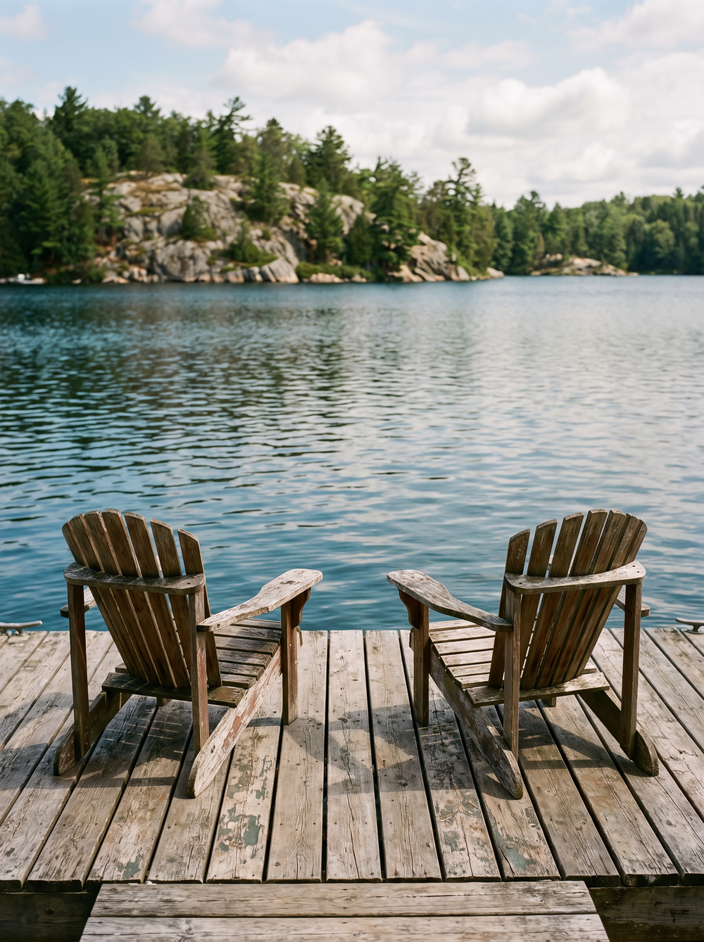 Two chairs on a cottage dock overlooking the lake
