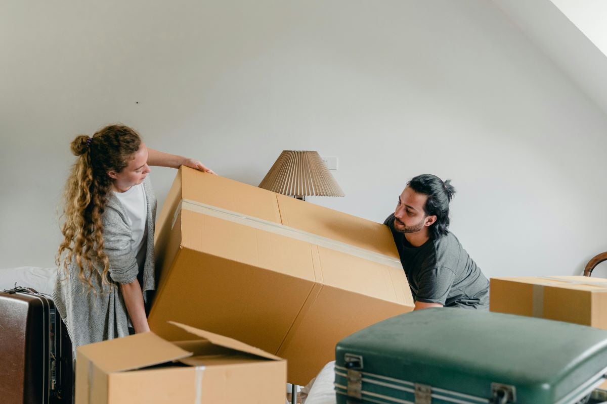 A couple moving into their new home and carrying boxes.