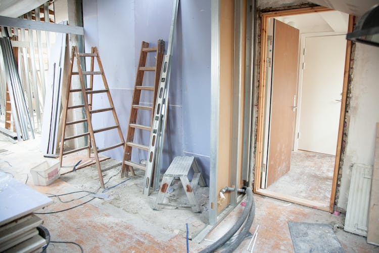 House under construction, ladders, dirt, and dust on the floors.