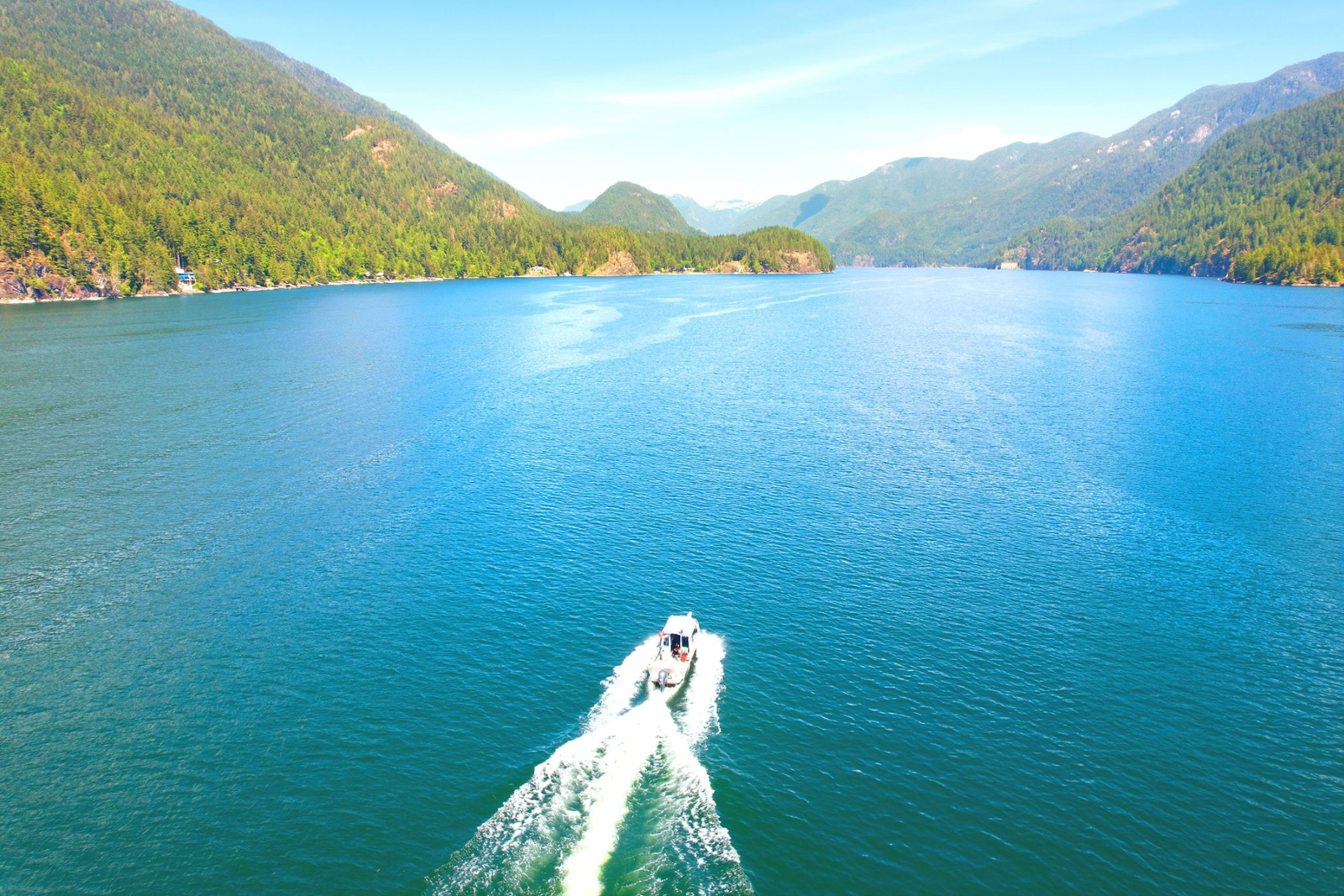 A boat on the calm water in Deep Cove, North Vancouver, with forested mountains in the background