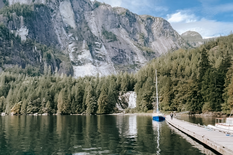 Sunshine Coast Regional District Waterfall with Blue Sailboat and Tall Mountains