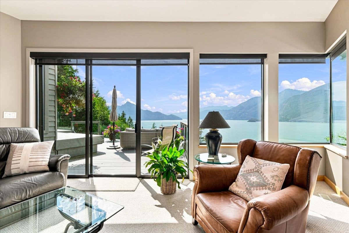 Interior view showing bright open-concept living room with floor to ceiling windows overlooking scenic views of Howe Sound water, islands and mountain views.