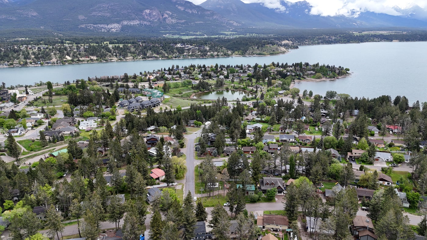 Aerial view of Invermere real estate showcasing homes, trees, lake, and mountain backdrop, highlighting scenic mountain living