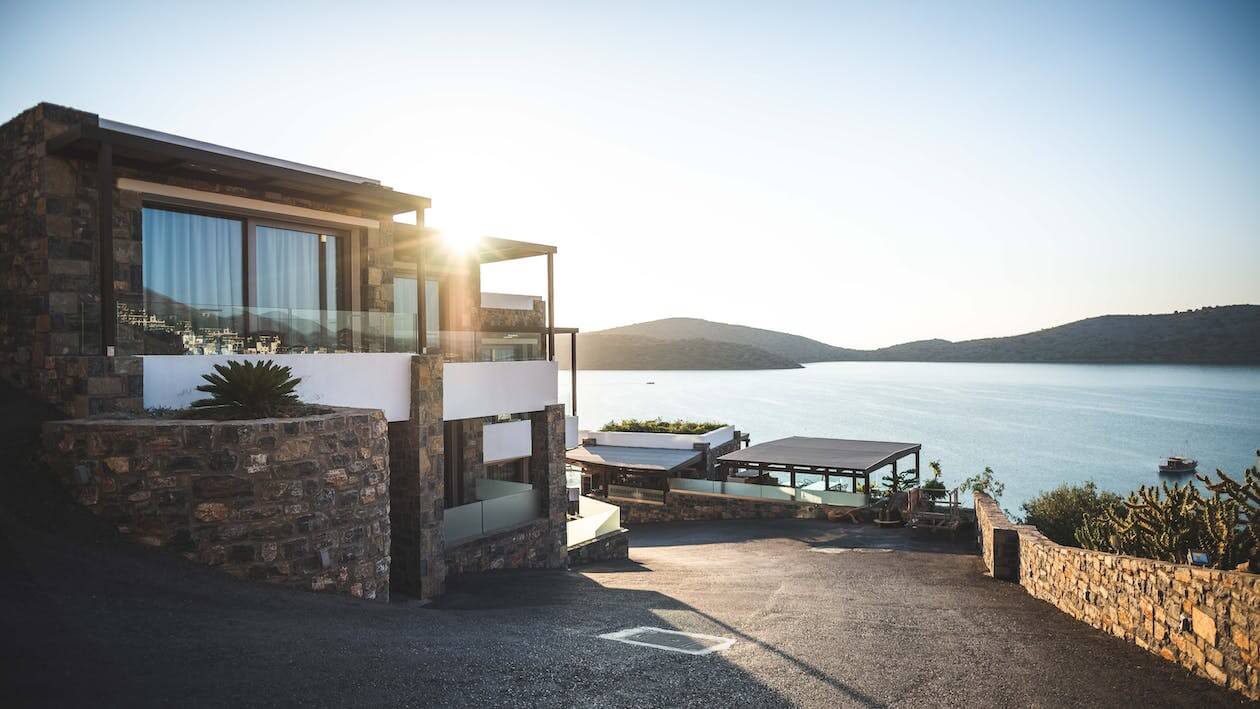 sun piercing over brown concrete house near lake