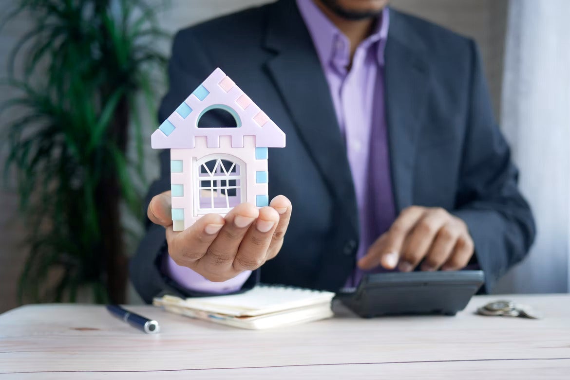 man in suit holding model house