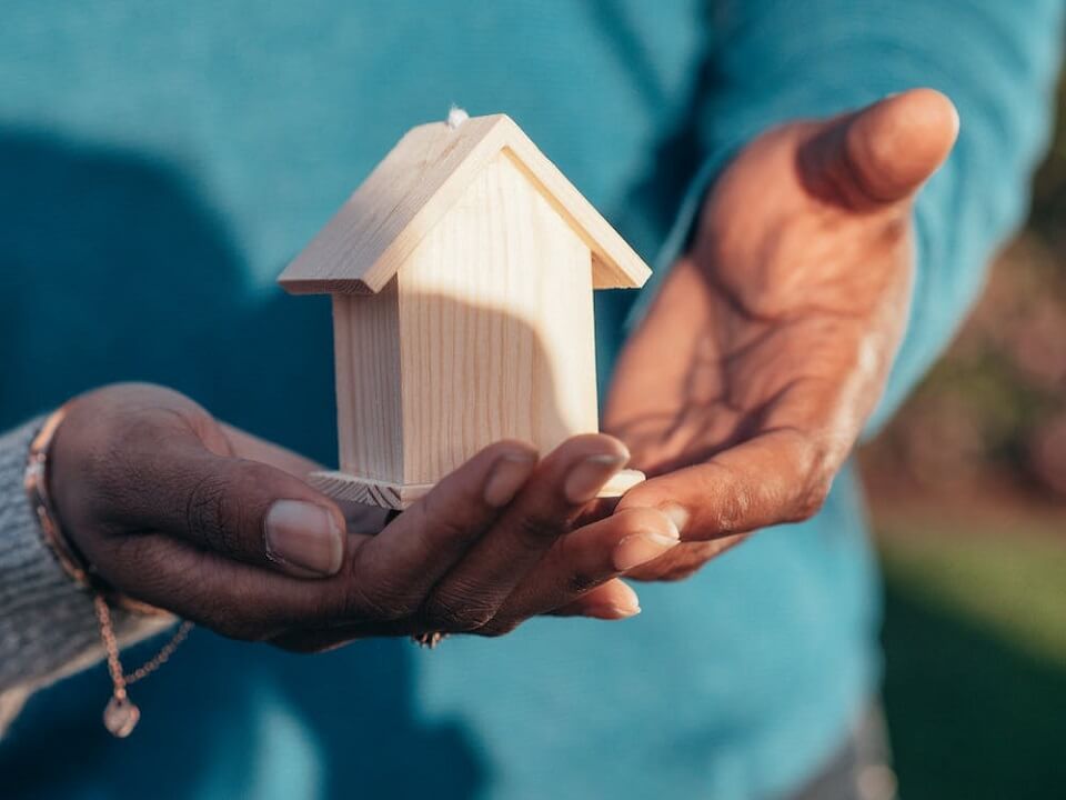 person holding small wooden house model