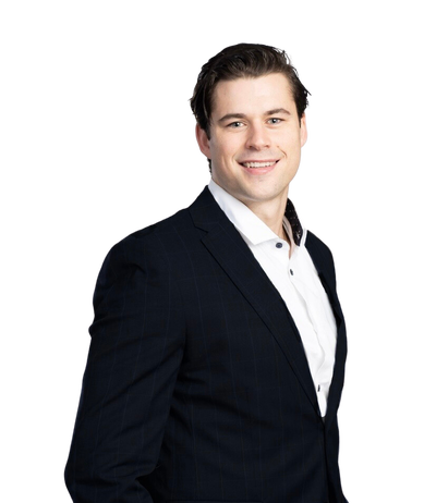 Portrait of RT Rice, Invermere realtor, wearing a black suit and white shirt, smiling confidently against a plain background