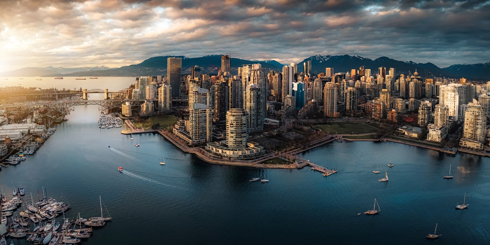Vancouver Real Estate Skyline – False Creek Aerial view of downtown Vancouver and False Creek with modern condos and mountains in the background.