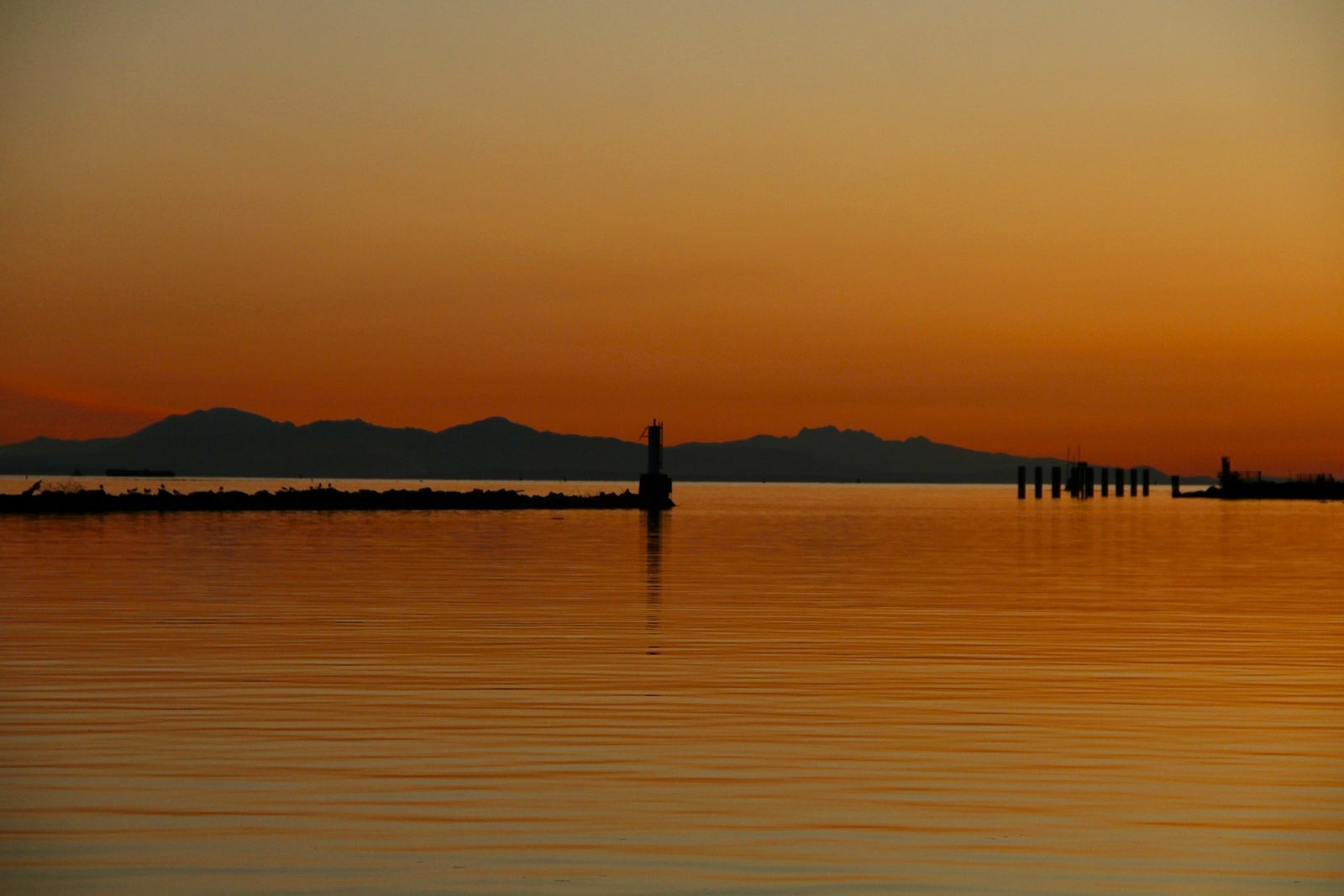Sunset view of Richmond BC waterfront with calm water and mountains in the background.