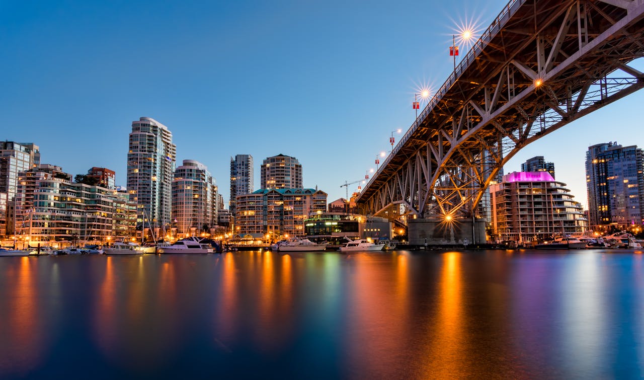Vancouver Downtown at Night – Property Management Night view of downtown Vancouver with high-rise condos, bridge, and waterfront boats, representing the city’s rental market.