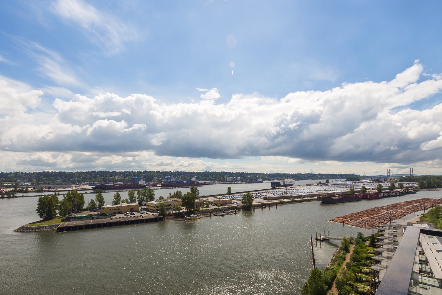 Aerial view of the Fraser River waterfront in New Westminster BC showing the river, shipping port, Queensborough area and Alex Fraser Bridge – My Dream Realty property management New Westminster